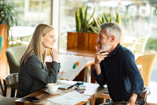Two business colleagues discussing reports at cafe