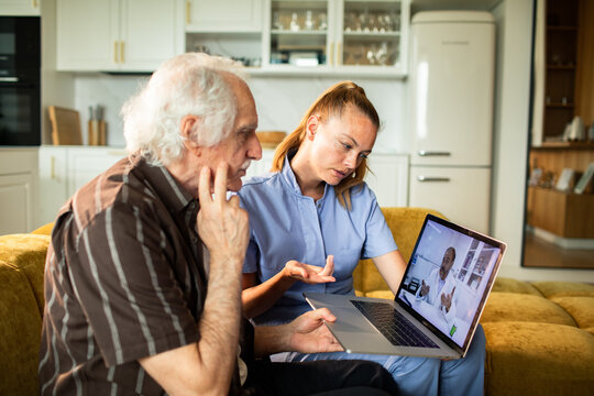 Nurse assisting elderly patient with telehealth video call at home
