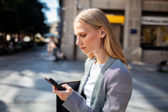 Young businesswoman using smartphone on city street