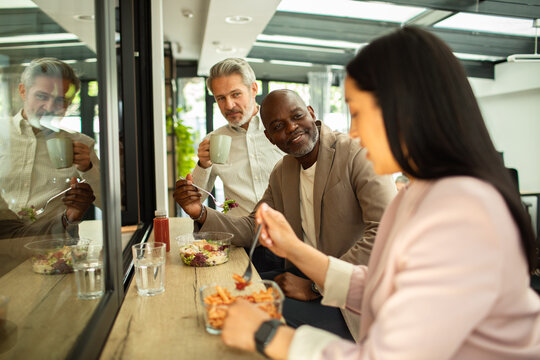 Coworkers eating lunch in modern office cafeteria