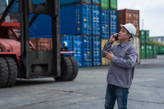 Container terminal team in safety gear discusses logistics beside colorful stacked shipping containers at the port.