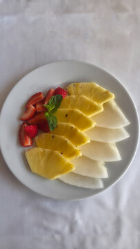 Detail of plated fruit: pineapple, strawberries, and apple