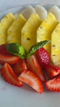 Detail of plated fruit: pineapple, strawberries, and apple