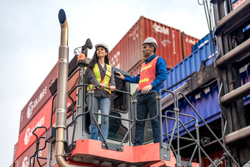 Naklejka premium Worker with a tablet inspects rows of stacked shipping containers at a busy import export freight terminal yard outdoors.