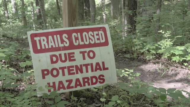 Trails closed due to potential hazards sign in woods 4k