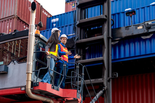 Forklift moves cargo between stacked shipping containers at a busy logistics shipping container terminal yard.