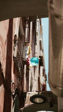 A basin lowered on a rope from the balconies of Naples in narrow streets