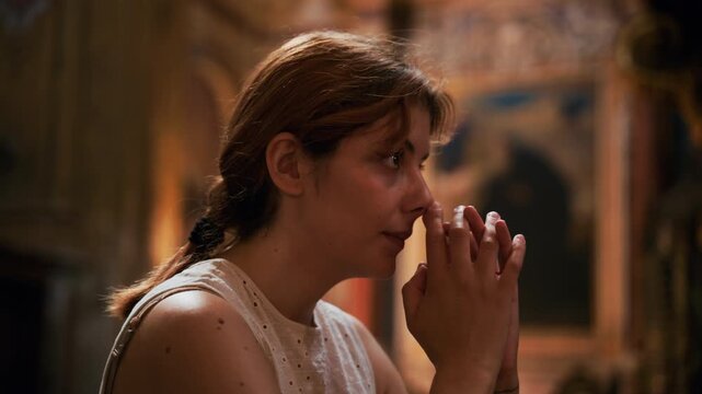 A woman prays with deep concentration in a sacred church in Naples