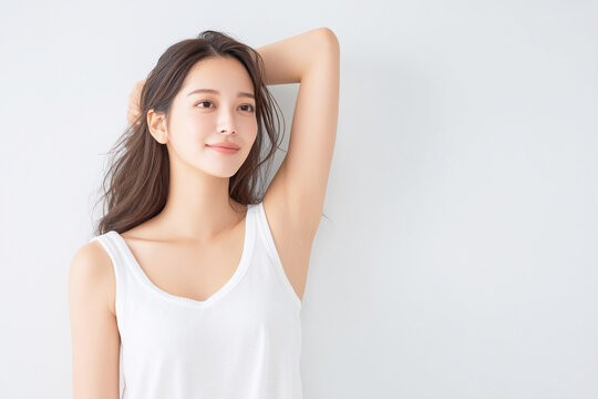 腕を上げて脇のムダ毛や肌をチェックする女性のボディケアイメージ
