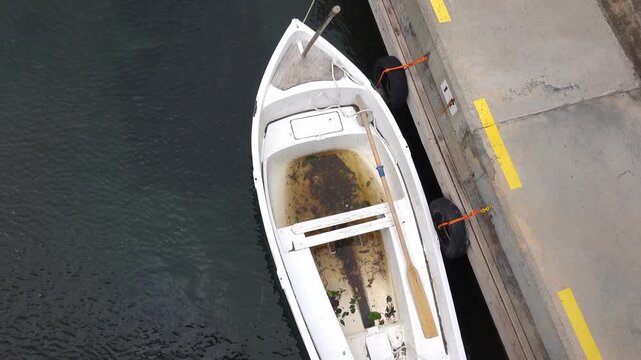Boat is at a dock with water inside and dirt