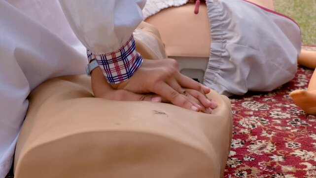 Close up of hands performing chest compressions on a CPR training manikin during a first aid demonstration. hands performing chest compressions on a resuscitation manikin during a first aid demonstrat