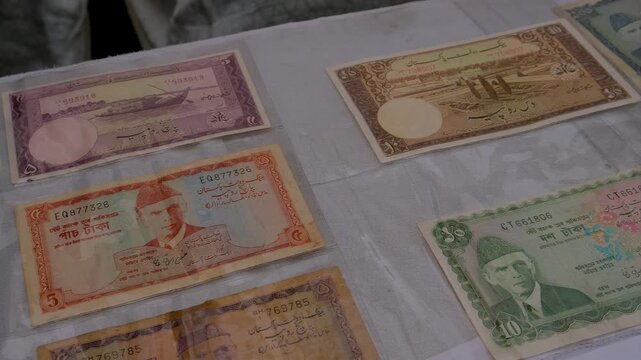 Old rupee and taka currency notes with commemorative coins and postage stamps arranged for a collectors' display, Antique paper money collection featuring historic South Asian banknotes, silver coins 