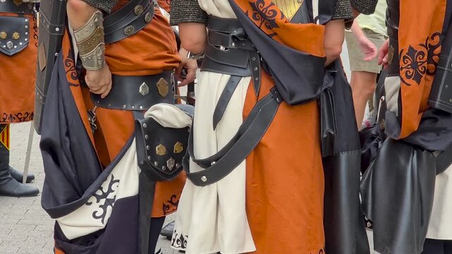 Midsection close up of participants in traditional medieval costumes during the Moros y Cristianos festival parade on the street.