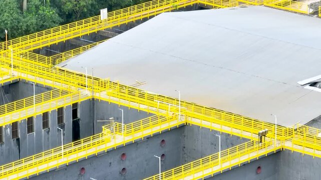 Wastewater treatment plant with circular clarifier tanks processing sewage. Urban sanitation and environmental infrastructure. Aerial drone view.