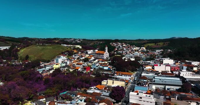 4K aerial drone view of a historic Catholic church surrounded by traditional houses and urban architecture in Santa Isabel, S&atilde;o Paulo, Brazil.