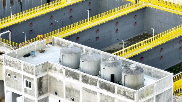 Wastewater treatment plant with circular clarifier tanks processing sewage. Urban sanitation and environmental infrastructure. Aerial drone view.