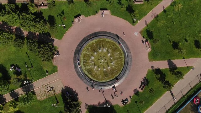Drone rises vertically above park fountain