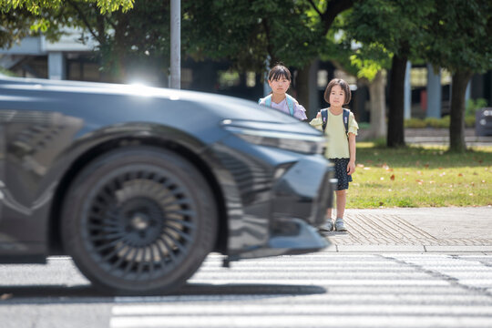 横断歩道を渡る子供たちと走行する自動車