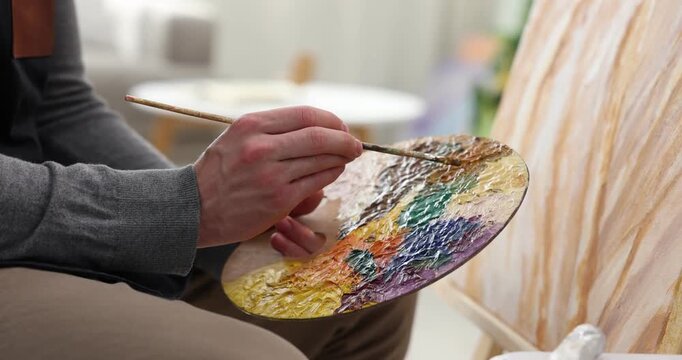 Man painting picture on easel in artist's studio, closeup