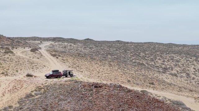 A teardrop camper trailer and SUV set up for dispersed camping in the dunes of Baja California by the Pacific Ocean near Guerrero Negro.