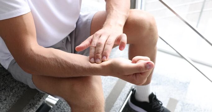 Man checking his pulse with fingers on stairs indoors, closeup
