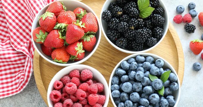 Different ripe berries in bowls on grey table, flat lay