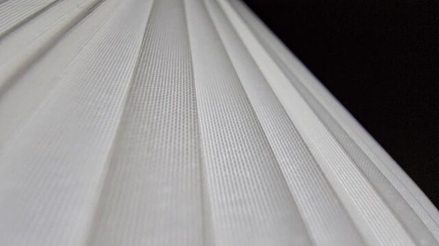 Close-up abstract shot of white pleated fabric or modern blinds showcasing horizontal parallel lines and clean minimalist textures.