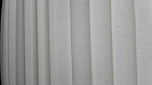 Close-up abstract shot of white pleated fabric or modern blinds showcasing rhythmic vertical parallel lines and clean minimalist textures.