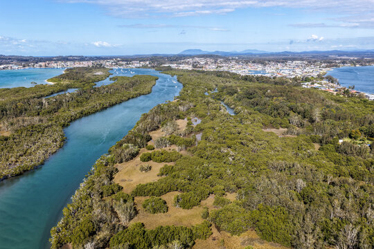 Aerial view from Settlement Point looking along the Hastings River towards Port Macquarie, showcasing the broad waterway, foreshore, surrounding coastal landscape and urban area in the distance 