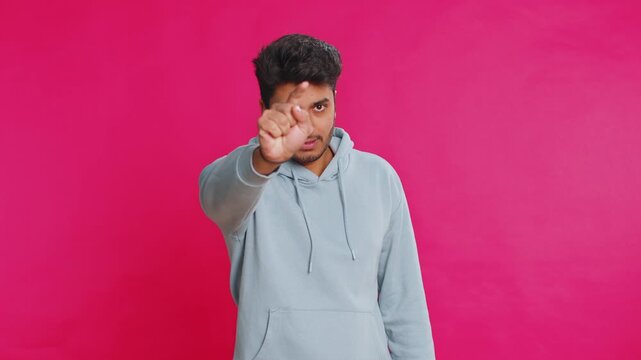 I choose you. Indian smiling man pointing finger to camera and looking with playful happy expression, making winner choice, showing direction. Arabian young guy isolated on pink studio background