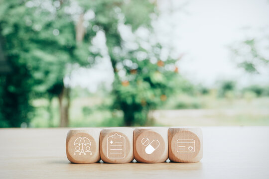 Wooden blocks with healthcare, medical insurance, family protection, prescription pills, and medical card icons on wooden table with green nature trees background, health insurance concept