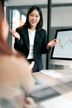 Asian Business Woman Gesturing and Explaining Financial Data in Office