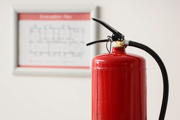 Obraz premium Fire safety and emergency preparedness, red fire extinguisher with an evacuation plan in the background
