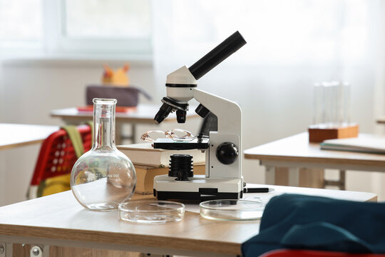 Science education and research, microscope with laboratory glassware on a classroom desk, scientific discovery and learning