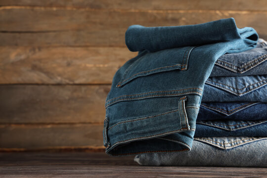 Sustainable fashion and denim clothing, stack of folded blue jeans on a rustic wooden background, textile industry and retail