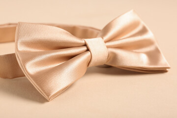 Stylish bow tie on beige background, closeup