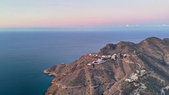 Aerial villas perched on rugged ridge at sunrise, winding roads and terraced gardens around private estates,