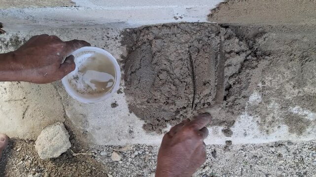 Construction Worker Mixing Concrete Mortar with Water by Hand for Wall Plastering and Building Renovation Project