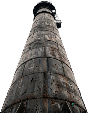 Low angle view of a towering weathered industrial metal smokestack constructed from riveted steel plates showing signs of corrosion and wear reaching upward toward the sky