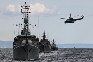 Fototapeta premium A helicopter flies over a formation warships during a naval exercise in the Black Sea