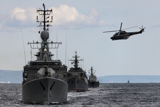 A helicopter flies over a formation warships during a naval exercise in the Black Sea