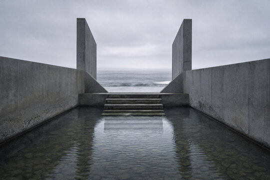 Minimalist concrete architecture, modern brutalist design, water reflection, ocean view steps, grey walls, abstract geometric structure, serene landscape with stormy sky background