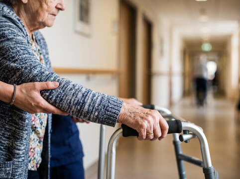 Caregiver Supporting Elderly Person Using Walking Frame