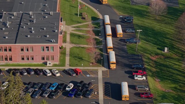Yellow school buses arriving at an American school campus captured by drone in autumn