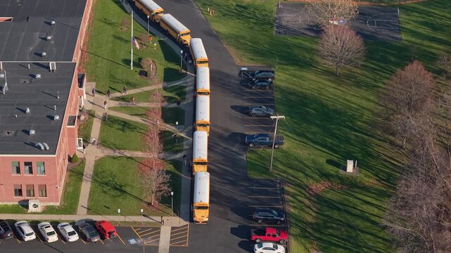 Drone view of students leaving an American school and boarding yellow school buses