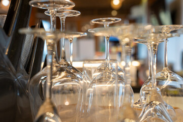 Obraz premium Clean empty wine and cocktail glasses resting upside down on a bar counter mat. Preparation for evening hospitality service at a modern restaurant lounge with blurred background.