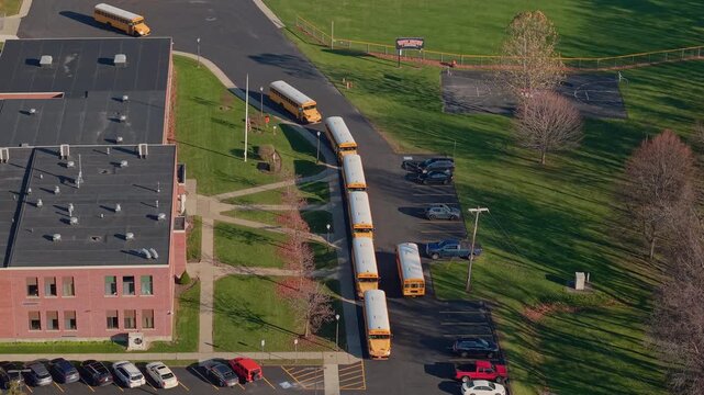Aerial view of yellow school buses lined up at an American school campus in autumn