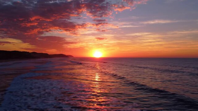Vivid sunset over the ocean horizon with glowing orange clouds and gentle coastal waves at dusk