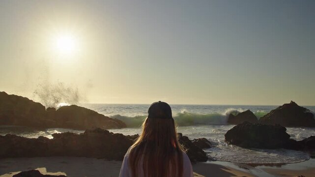 Woman Watching Waves Splash Against Rocks at Sunset in Portugal