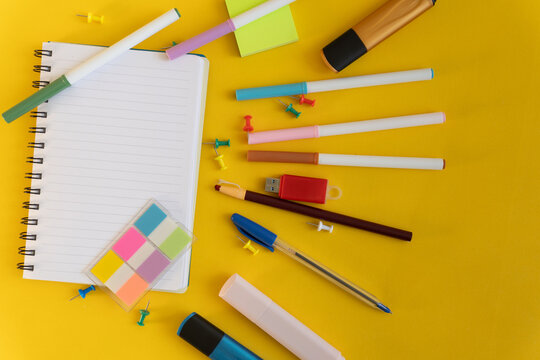 Colorful office supplies and notebook on yellow surface - creative workspace con